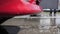 Water and foamed detergent drains from a red washed car in a self-service car wash