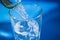 Water glass, pouring water, blue background, splashes