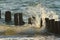 Water hits the wooden piles driven into the sea