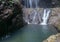 Water from a lake under a waterfall overflows a rock. Madakaripura Waterfall is located not far from Mount Bromo.