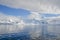 Water lay still under low hanging white clouds that cover Antarctic mountains