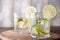 Water with lemon and lime in glasses, detox concept on wooden background