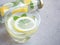 Water and lemons slice in glass with mint leaves and bottle on grey background