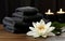 water lillies lotus flowers with stack towels and black spa stones on wooden background