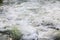 Water in the mountain raging river. Beautiful natural background of stones and water. Texture of clear water and fast river