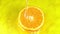 Water pours on an orange juicy orange on a yellow background slow motion closeup. Orange slice and water splashing and