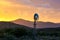 Water Pump Windmill on Arid Farmland at Sunset