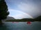 Water rafting with half rainbow on land in sunny blue sky