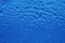 Water rain drops on glass surface in trendy color of the years classic blue. Abstract background backdrop