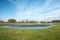 Water after rain on green meadow, clouds on blue sky