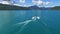 Water skiing on lake aerial view. Riding water board ski behind motorboat.