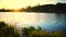 Water of the small lake slowly moving in sunset with small house on the shore