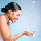 Water splash, hands and black woman isolated on blue background for face skincare, cosmetics or hands cleaning. Person