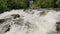 Water splashing on the rocks and stones. River stream rapidly flowing over cascade in nature.