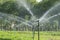Water springer sprayed In the garden with green background.
