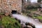 Water stream coming out of a traditional old water mill in full