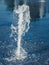 Water stream flowing out of stainless grate of dry fountain, close up view. Liquid splashing on granite square coating