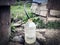 Water supply shortage and climate change threats: collecting drinking water with 5 liter plastic water bottle from a well in a rur