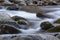 Water swirling over large rocks in a cold mountain stream