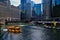 Water taxis carry morning rush hour commuters across the Chicago River, with view of art and lounge chairs on the riverwalk.