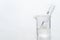 Water in test tube and glass science beaker in white chemistry background