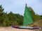 Water tourism. Kayak with a sail on the sandy shore. Water trip. The banks are overgrown with reeds