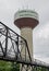 Water Tower Behind Century Old Pedestrian Bridge In Small Town