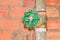 Water valve plumbing joint steel old tap pipe with green knob on brick background