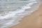 Water washing sand on the beach on overcast day. Detail on small white waves forming. Abstract sea background