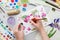 Watercolor drawing - pink cherry flowers - and artistic equipment on desk. Painter drawing at working place