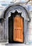 Watercolor illustration of a beautiful antique wooden orange door under a carved stone arch