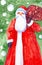 Watercolor illustration of Santa Claus with a bag of gifts on the background of a Christmas tree and falling snow