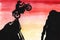 Watercolor image of motorcyclist jumping over gap between rocks on his motorcycle. Dark silhouettes against bright background of