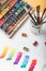Watercolor paints, paintbrushes and colorful paint strokes in drawing album at designer workplace