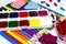 Watercolor paints, pencils of different colors, plasticine and erasers, buttons and paper clips isolated on a white background