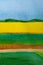 Watercolor sunny landscape with yellow sunflowers field on the horizon with blue sky and green grass meadows in front. Vertical