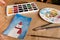 Watercolour seasonal greetings postcards on a table with palette and brushes