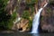 Waterfall and brown cliff beautiful with sunshine