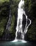 Waterfall cascade in tropical rainforest with couple in love bathing underneath