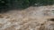 Waterfall cataract in forest mountains. Dirty streams are flowing down the mountain slopes of the mountain forest after heavy