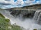 Waterfall Dettifoss with rainbow, black basalt columns and water spray in sunny summer day. Northern Iceland, Europe