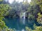 Waterfall in the distance sounded by trees in Plitvice. Croatia