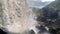 Waterfall falls over the stones and turns into a turbulent mountain river.