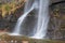 a waterfall flowing down a rocky cliff near some water and vegetation