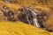 A waterfall flowing down a steep mountain slope on Streymoy Island, Saksun, Faroe Islands