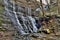 Waterfall flowing over aged and mossy grey rocks