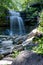 Waterfall Flows down a Rocky Cliff in a Forest