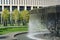 Waterfall flows in streams into granite bed. Fountain in form of huge bowl on Krasnodar stadium background. Public landscape city