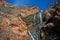 WATERFALL AND GREEN VEGETATION AGAINST SHEER ROCK