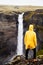 Waterfall Haifoss in Iceland. A young guy stands on a cliff and looks at the waterfall.